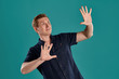 © nazarovsergey - Close-up portrait of a ginger guy in navy t-shirt posing on blue background. Sincere emotions.