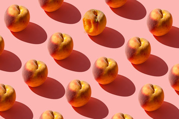 A pattern of many juicy ripe peaches on a pastel pink background. Creative layout