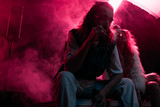 Fototapeta  - man smoking cigarette near young woman during rave party in nightclub