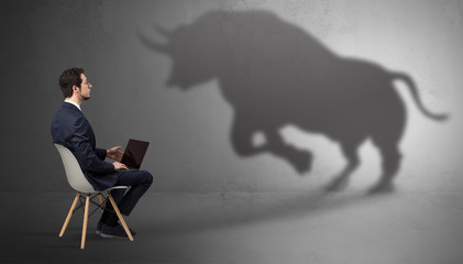 Canvas Print - Humble businessman staying and offering stuffs to a huge angry bull shadow