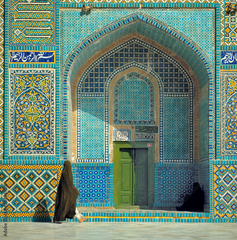 Afghanistan, Mazar-i-Sharif. A chadri-draped woman passes an archway at the Shrine of Hazrat Ali in Mazar-i-Sharif in Afghanistan.