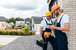 © LIGHTFIELD STUDIOS - happy handyman holding toolbox near cheerful coworker using digital tablet