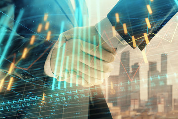 Double exposure of financial graph on cityscape background with two businessman handshake. Concept of stock market deal