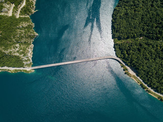 Aerial footage a car driving over a bridge on Piva Lake