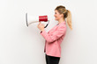 © luismolinero - Young blonde woman with pink suit shouting through a megaphone