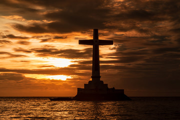 Wall Mural - Dramatic Sunset Sky Behind a Large Cross Marking a Sunken Cemetery on Camiguin Island, Philippines