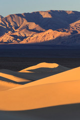 Poster - Hikers walk during sunrise along the ridgeline of a sand dune in the Mesquite Dunes complex inside Death Valley National Park.