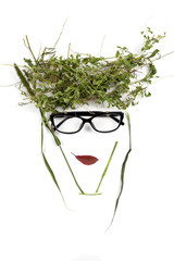 Wall Mural - Abstract face of a young fashionable woman in eyeglasses. A creative fashion image of a female portrait made of plant materials of grass and leaves. Flat lay