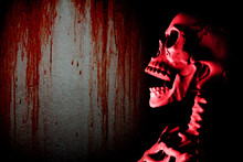 Fake Human Skull Head And Dark Gloomy Wall With Red Blood Stain Background, Halloween Concept.