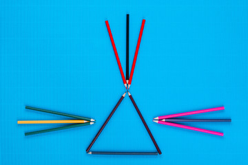 Wall Mural - A bunch of crayons forming arrows on an blue background, shot from above.