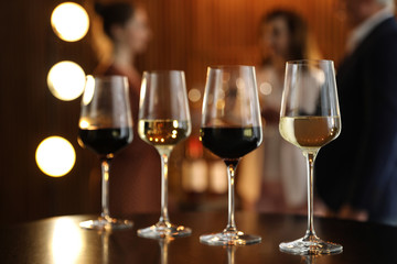 Glasses of different wines on table against blurred background