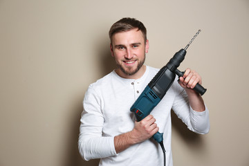 Sticker - Young working man with rotary hammer on beige background