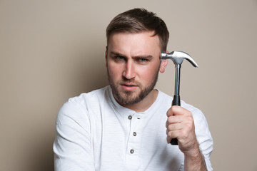 Poster - Young working man with hammer on beige background