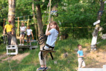 Wall Mural - Little girl on zip line in adventure park. Summer camp