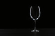 Empty wine glass on table against black background, space for text