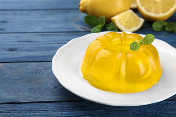 Plate with lemon jelly and mint on blue wooden table. Space for text