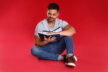 Sticker - Handsome young man reading book on red background