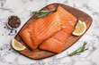 Wooden board with salmon fillet on marble table, flat lay