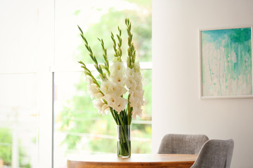 Canvas Print - Vase with beautiful white gladiolus flowers on wooden table in room, space for text