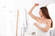 © New Africa - Beautiful young woman applying deodorant after shower in bathroom. Space for text