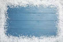 Frame Of White Snow On Blue Wooden Background, Top View With Space For Text. Christmas Season