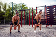 © zamuruev - Two Athletic men working out with a kettlebell at street gym yard. Strength and motivation. Outdoor workout.