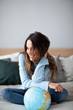 © BestForYou - Happy smiling woman with a globe on bed.