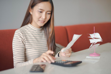 Closed up and focus on hand of young woman using a calculator and other hand take a bill which sitting on sofa and work on the table at cafe or co working space. co working space concept.