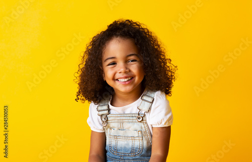 Cuadros en Lienzo Happy smiling african-american child girl, yellow background