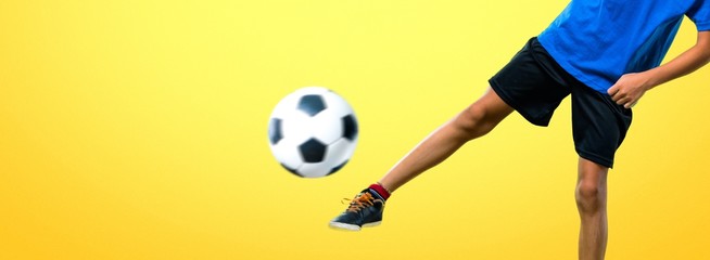 Canvas Print - Boy playing soccer kicking the ball on yellow background