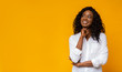 Young afro girl dreaming on yellow background