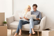 © Prostock-studio - Couple sitting on couch reading design project documents on laptop