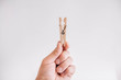 Male hand holding wooden clothespin on white background