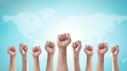 International human rights or labor day with Hands with clenched fist of people crowd (men and women) isolated on world map and sky background