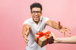© denis_vermenko - Cheerful smiling african american millennial guy in eyewear holding wrapped present box. Happy black young man congratulating, giving birthday gift, isolated on pink background.