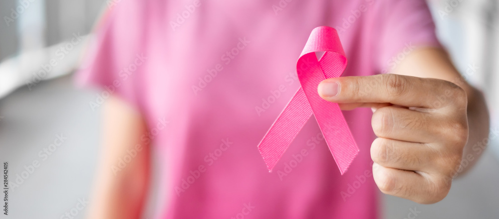 October Breast Cancer Awareness month, Woman in pink T- shirt with hand holding Pink Ribbon for supporting people living and illness. Healthcare, International Women day and World cancer day concept - obrazy, fototapety, plakaty 