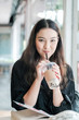 © amnaj - Charming Asian woman sitting drinking pearl milk tea happily.
