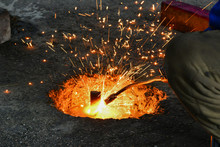 A Gas Cutter In Production, A Welder Removes Unnecessary Metal Residues With A Gas Cutter, Sparks Fly In Different Directions.