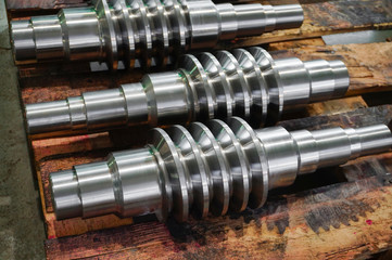 The worm shaft after processing lies on a wooden rack, the production of helically screw products.