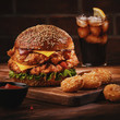 © FoodAndPhoto - Fresh tasty homemade burger on wooden table. Big double cheddar cheeseburger with chicken cutlet with french fryes.