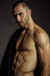© Oleh Phoenix - Strong stripped muscle male model in black fabric on black isolated font background