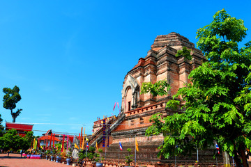 The old pagoda built from brown bricks in Thailand at the top has disappeared, is located in a temple area with trees on the side in the daytime and behind the sky.