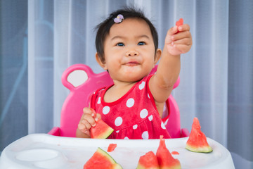 Asian baby girl eating watermelon.