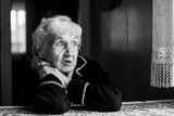 Fototapeta  - Black and white portrait of an old grandmother sitting at the table.