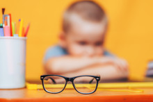 Boy Sitting Ubfocused Glasses In Focus. Concept Problem Of Ophthalmology Correction Of Myopia. Back To School. Selective Focus. Upset Child