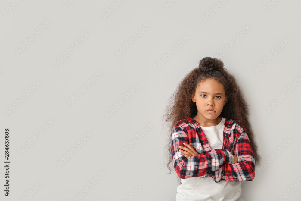 Bored African-American girl on light background