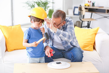 Grandfather teaching little boy to repair clock at home