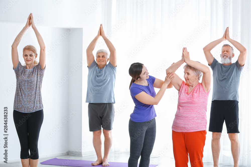 Young trainer helping elderly woman during training in nursing home
