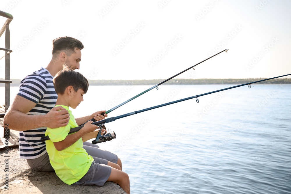 Father and son fishing together on river