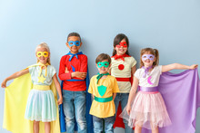 Cute Little Children Dressed As Superheroes On Color Background